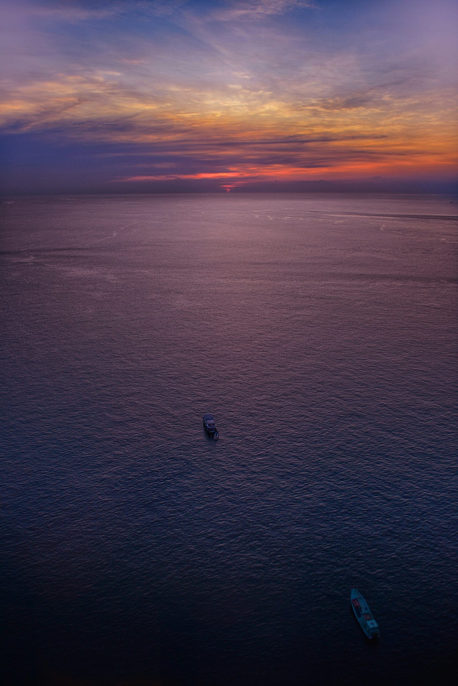 two boats on body of water under blue and orange sky